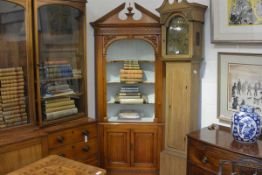 A George III style pine corner cupboard, with broken pediment above open painted shelves, over a