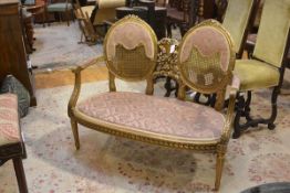 A giltwood canape, late 19th century, with twin oval canework back divided by a ribbon-tied floral