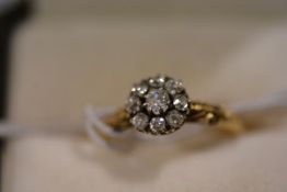 An early 20th century 18ct gold diamond cluster ring, the flowerhead plaque centred by a brilliant-