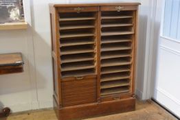 An Edwardian oak stationery cupboard, the rectangular moulded top above a pair of tambour doors