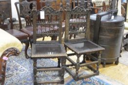 A pair of carved oak hall chairs, c. 1900, each with spindle carved back between uprights surmounted