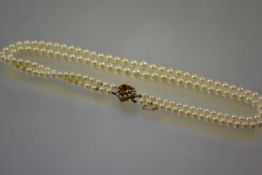 A twin-strand graduated cultured pearl necklace, set on a heart-shaped clasp centred by a conforming