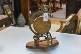A Chinese brass table gong, the frame cast with a dragon suspending a gong engraved with fish, on