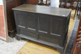 An 18th century oak and elm coffer, the hinged planked top (lacking hinges), above a panelled