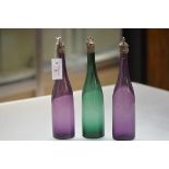 A set of three 19th century coloured glass bottle decanters, each of slender form, two in amethyst