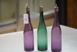 A set of three 19th century coloured glass bottle decanters, each of slender form, two in amethyst