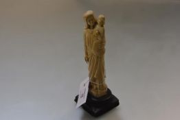 A 19th century ivory carving of the Virgin and Child, on a carved oak base (losses, cracks). Ivory