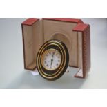 A Must de Cartier gilt-metal and lacquer cased travelling alarm clock, the oval case in black