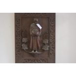 A carved wooden panel of a buddhist monk, in high relief, depicted standing, holding an alms bowl