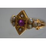 An Edwardian ruby, diamond and seed pearl 18ct gold ring, the central plaque inset with an oval-