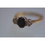 An 18ct gold three stone sapphire and diamond ring, the central oval-cut sapphire flanked by a