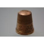 A yellow metal thimble, stamped "9", engraved with date 1900. 5.6 grams