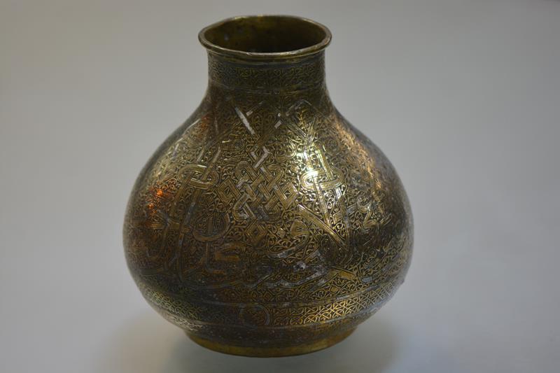 A late 19th century inlaid brass vase of Mamluk type, decorated in mixed metals with scrolls and
