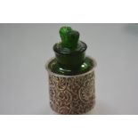 An Edwardian silver-mounted green glass scent bottle, the silver sleeve chased with scrolls and