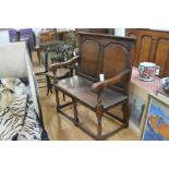 A small oak settle in early 18th century style, with twin fielded panel back over a plank seat