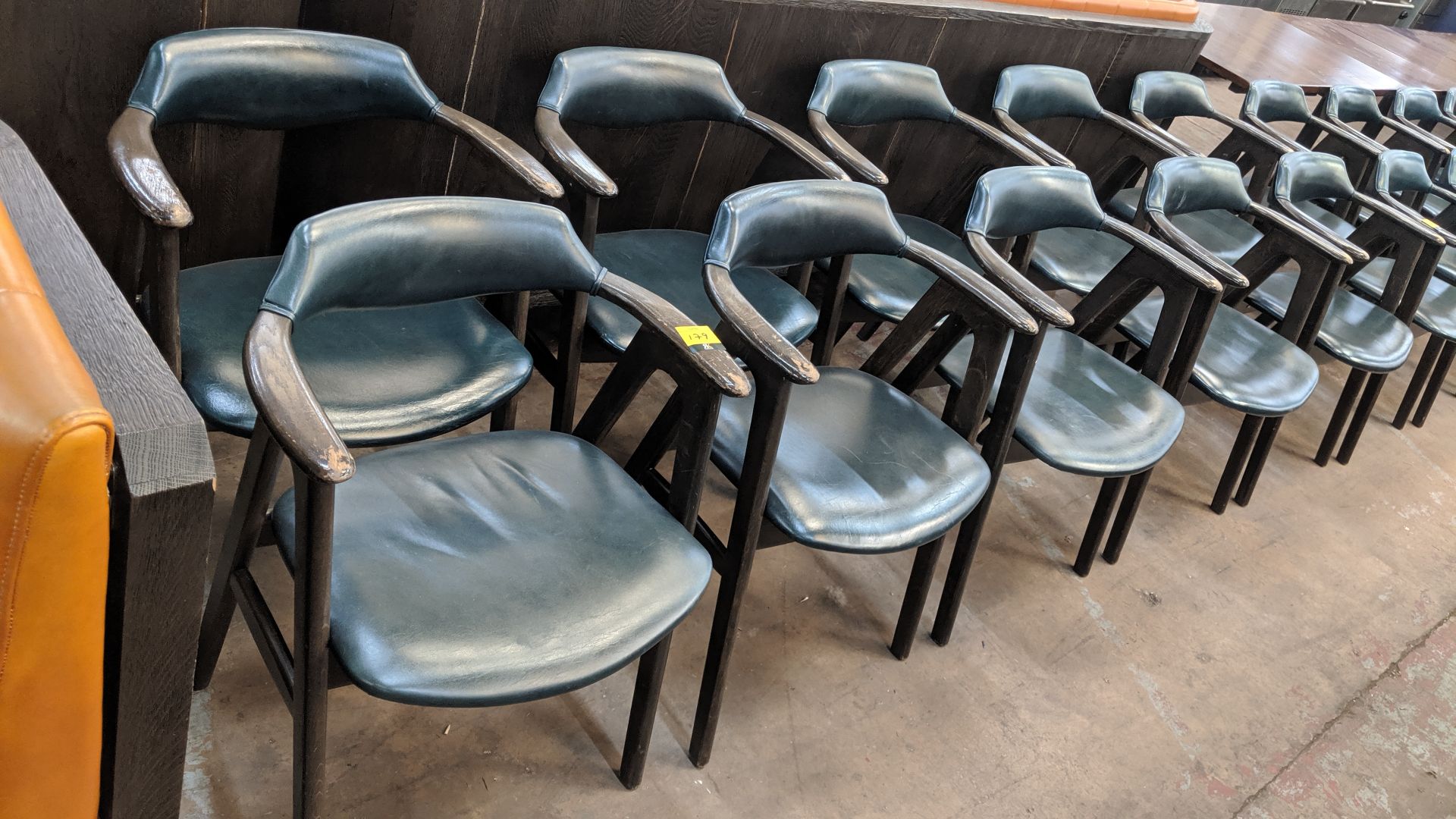 10 off upholstered wooden dining chairs with arms in a dark teal leather/leather type covering. NB - Image 2 of 4