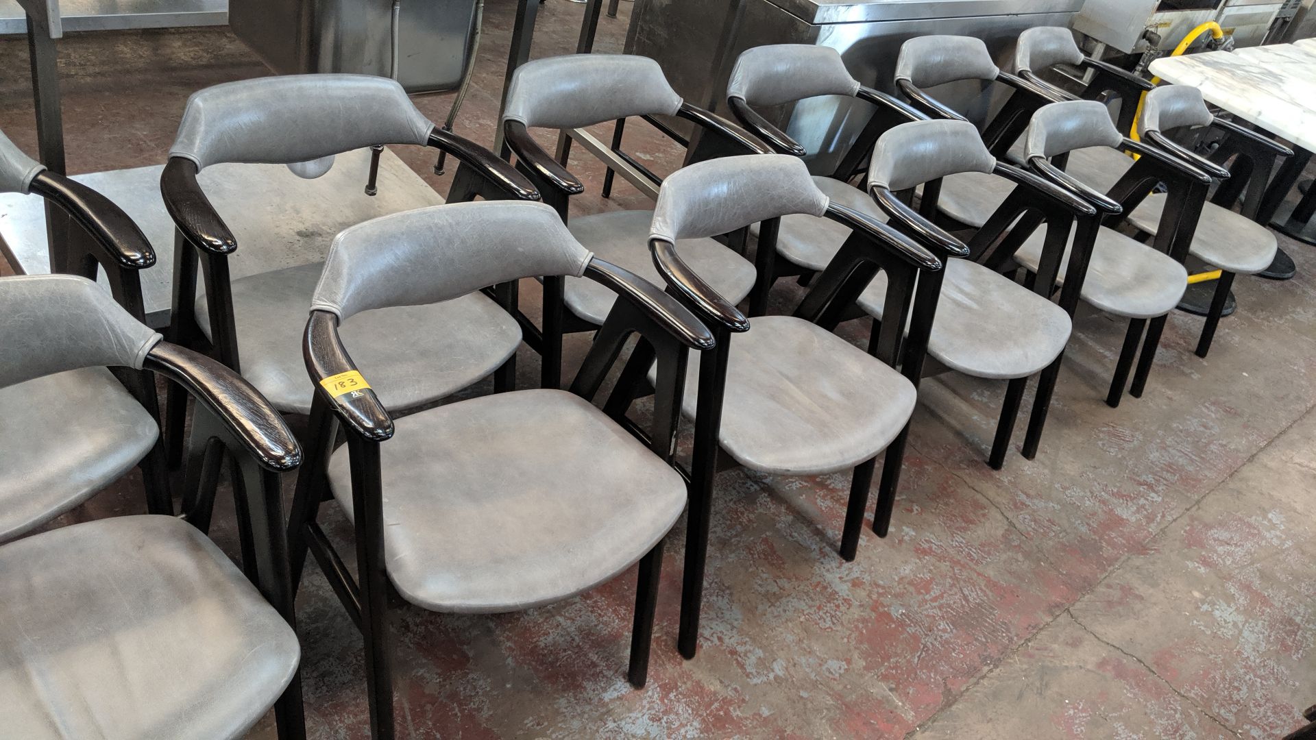 10 off upholstered wooden dining chairs with arms in a pale grey leather/leather type covering. NB