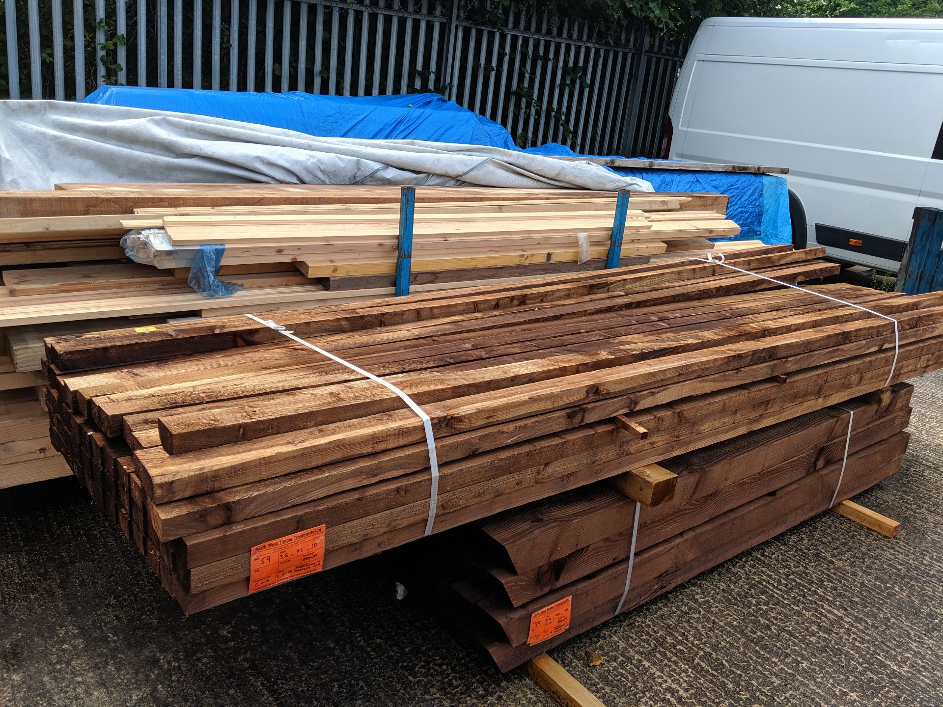 Bundle of approximately 56 brown treated fence posts, indicated on a label as being 3.6 x 75 x 50,