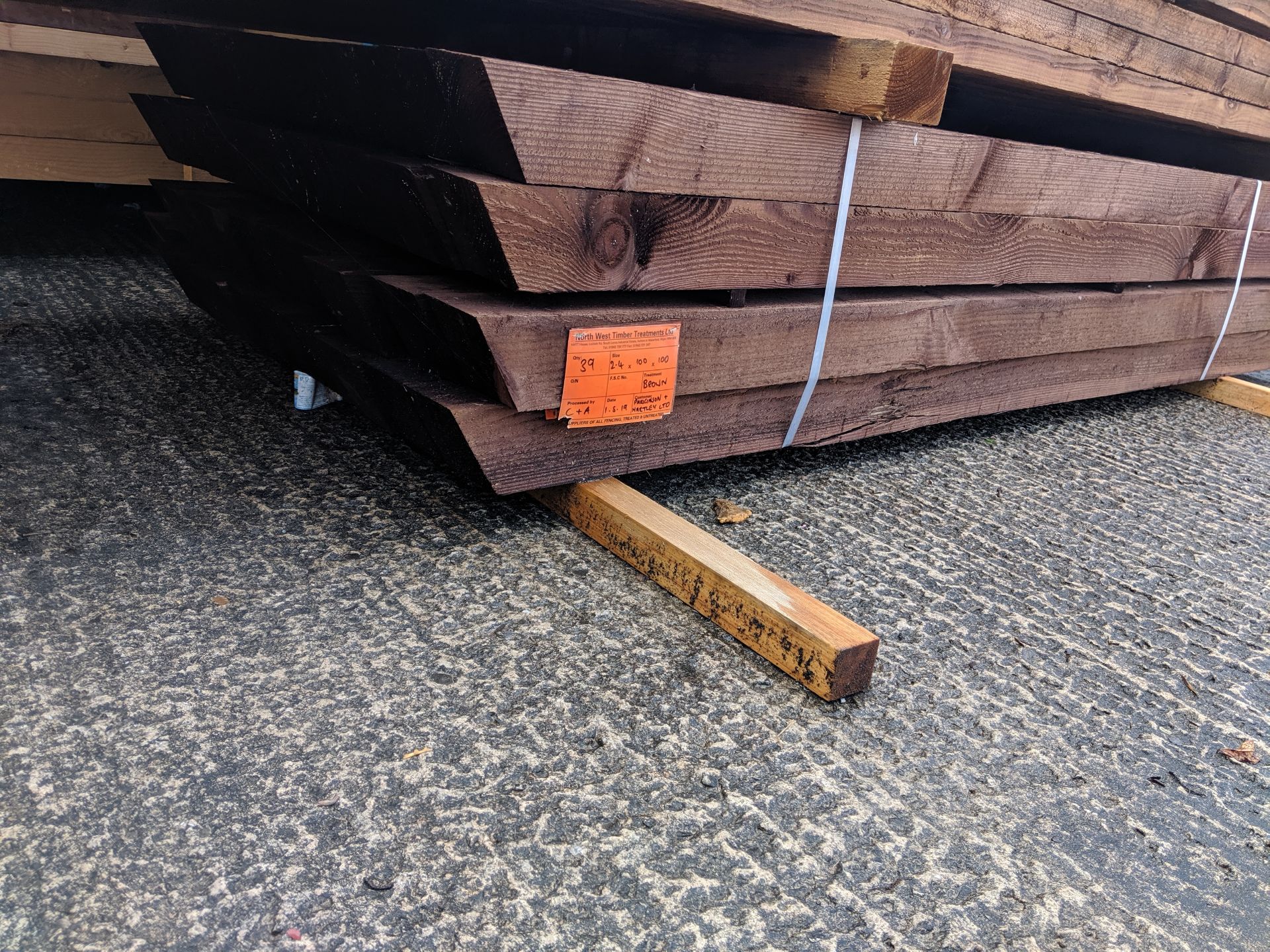 Bundle containing approximately 39 brown treated fence posts, indicated on a label as being size 2.4