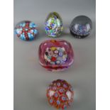 Four vintage millefiori decorated paperweights and a similar bowl with cranberry tint