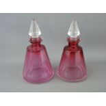 Pair of conical cranberry glass scent bottles with facet cut clear stoppers