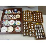 Collection of china thimbles and miniature wall plates in display units