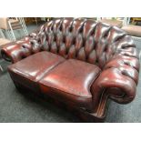 A two-seater burgundy leather Chesterfield-type settee Condition reports are provided on request