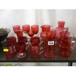 Four cranberry glass jugs, a quantity of custard cups and other cranberry glassware