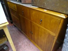 Oak mid Century sideboard having a mixed arrangement of drawers and cupboards with central drop down