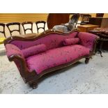 An antique serpentine back settee with roll sides and on turned supports, having pink purple