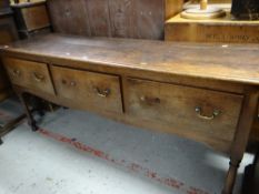 A nineteenth century oak three-drawer dresser base on turned and block supports, 181cms wide