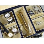 A monogrammed vintage jewellery box containing various items including watches, propelling