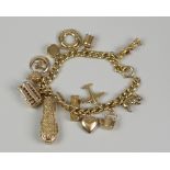 18CT YELLOW GOLD CURB LINK CHARM BRACELET having an assortment of 9ct gold charms to include a cased