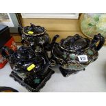 Three black lustre teapots, one on a small base tray