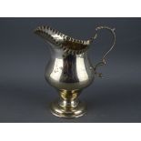 A HELMET SHAPED SILVER CREAM JUG on pedestal base with scroll handle, Chester 1920 (crease to the