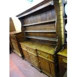 AN EARLY 19th CENTURY NORTH WALES OAK BREAKFRONT DRESSER, the shape sided three shelf rack over a