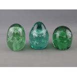 THREE VICTORIAN GREEN GLASS DUMP PAPERWEIGHTS, all having floral inclusions, 11 cms high the