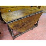 AN OAK TWIN FLAP GATE LEG DINING TABLE with single end drawer in the antique style on turned and