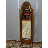 A CIRCA 1930 WALNUT FRAMED CHEVAL DRESSING MIRROR with shaped top bevelled edge glass, 146 cms high,