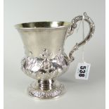 An early Victorian repousse work footed mug with scrolling loop handle and with silver gilt