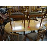A mid-century oval extending dining table having a pop-up centre leaf and six matching chairs (G-