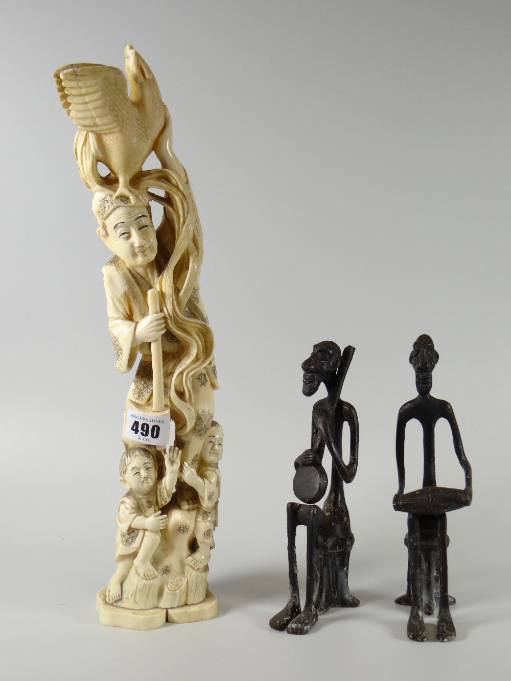 A Meiji carved ivory stack-group of a jolly father & his two children with bird atop and two