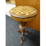 An antique circular topped marquetry games table / sewing box on carved tripod supports, 46cms diam.