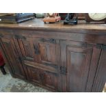 A Jacobean-style panelled oak sideboard with metallic hinges & fittings, 102cms h x 160cms l x 50cms