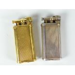 Two Dunhill gas cigarette lighters, gold metal engine turned and white metal ribbed body example