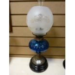 Metal stemmed oil lamp with blue glass reservoir and etched shade
