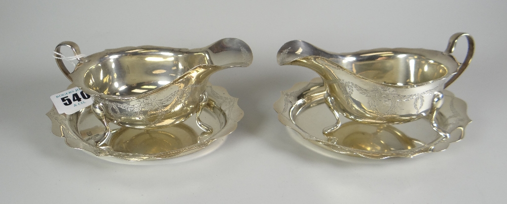 A pair of Elizabeth II silver sauce-boats on stands with matching garland decoration, on three pad-