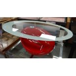 A contemporary coffee table of oval form with glass top and having red plastic base of abstract