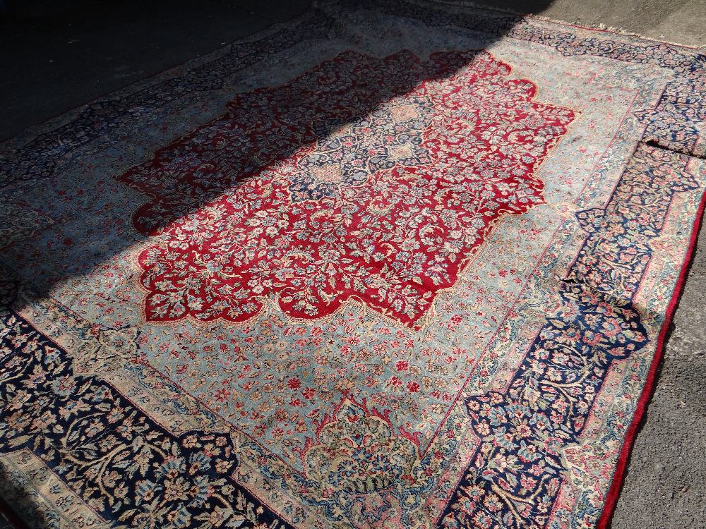 A large Persian Kashan rug with red centre decoration and blue and gold border, 410 x 292cms (A/F)