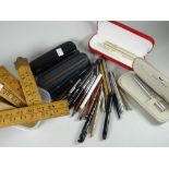 A plastic tub of Sheaffer and other fountain pens and a parcel of vintage wooden folding rulers